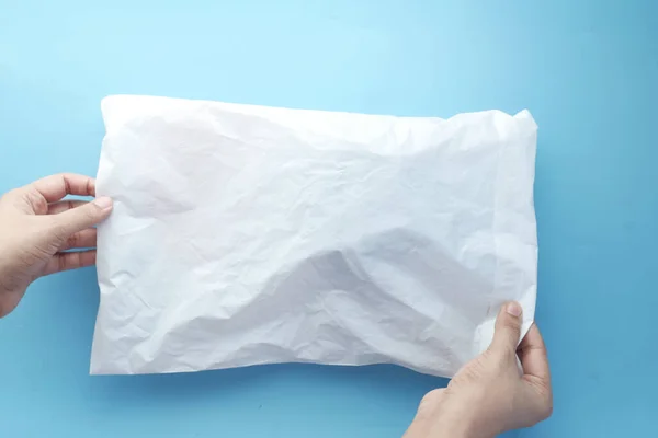 holding white paper bubble envelope for postal ship.