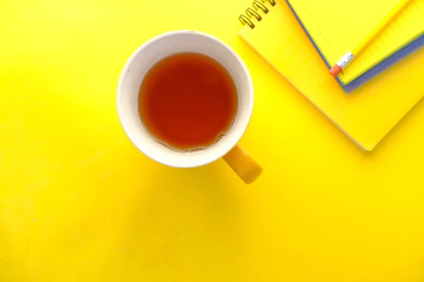 Burla taza de color amarillo con cuadernos sobre fondo amarillo — Foto de Stock