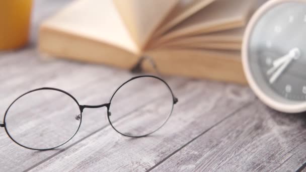 Open book, mug, eyeglass and a pencil on wooden table — Stock Video