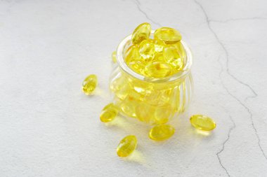 Beyaz arka planda bir kabın içinde balık yağı takviyesi 