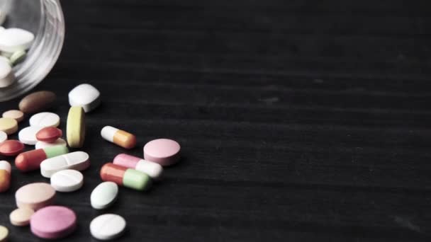 Close-up de muitas pílulas coloridas e cápsulas em fundo preto — Vídeo de Stock