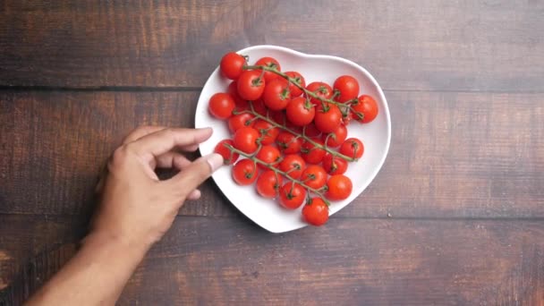 Ruční sběr třešeň čerstvé rajče na stole tvaru srdce — Stock video