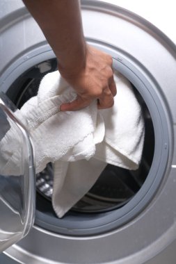 bir çamaşır makinesine havlu ve bez koymak.