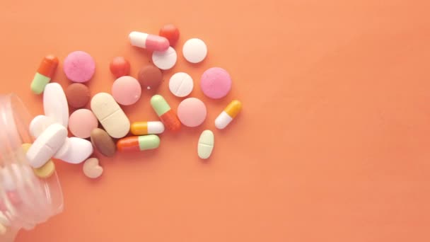 Close up of many colorful pills and capsules on orange background — Stock Video