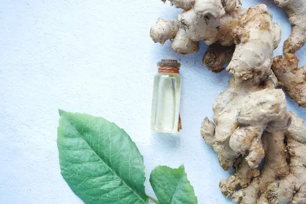 Primer plano del aceite de jengibre y la hoja en la mesa —  Fotos de Stock