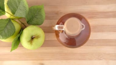 Cam şişede elma sirkesi ve masada taze yeşil elma. 