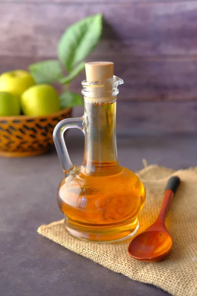Cuka apel dalam botol kaca dengan apel hijau segar di atas meja — Stok Foto