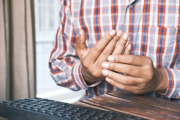 Man suffering pain in hand while working on table — Stockfoto