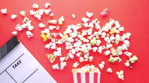 Película clapper board y palomitas de maíz sobre fondo rojo — Vídeo de stock