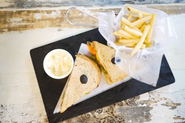 Bir dilim biftekli sandviç ve patates kızartması masada. 