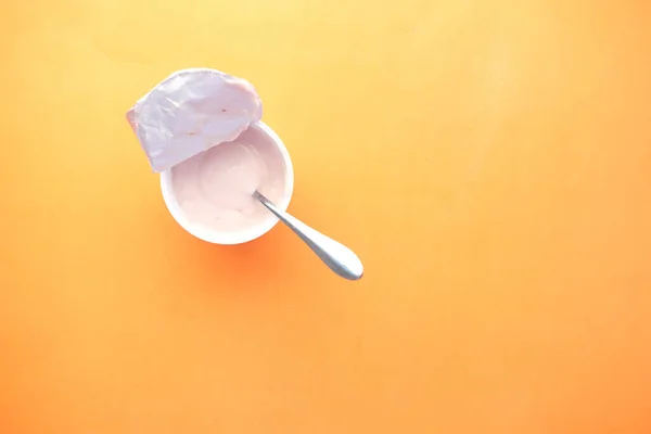 Свіжий йогурт у пластиковій тарі на помаранчевому фоні — стокове фото