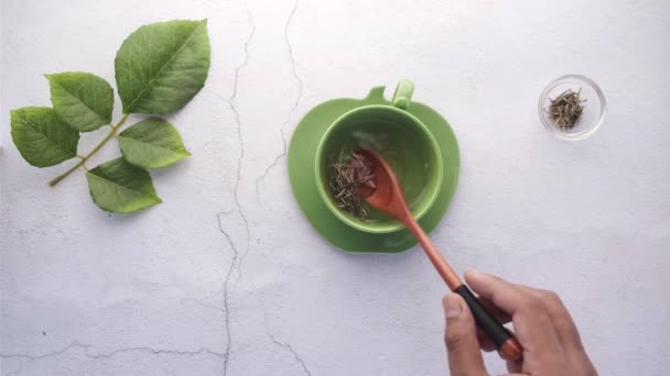 Hand in spoon mixing herbal leaf with hot water — Stock Video