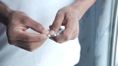 Genç adam su toplamış bir paketten ilaç alıyor. 