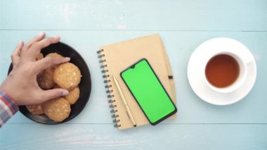 Akıllı telefon, kurabiye ve çayın üst görünümü 