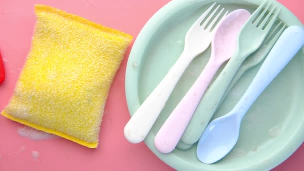 Sponge , rubber gloves and colorful plate on pink — Stock Video