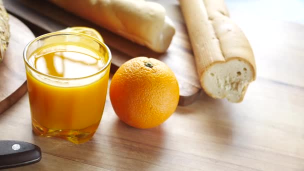 Vaso de jugo de naranja y pan integral en la mesa — Vídeos de Stock