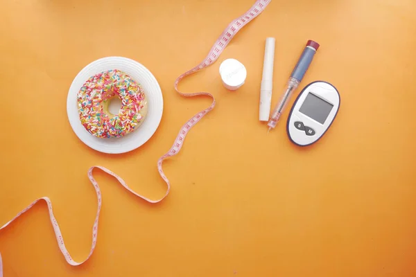 Diabetische meetinstrumenten, insuline en donuts op roze — Stockfoto