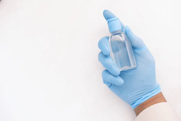 Mano en guantes que sostienen el desinfectante de la mano sobre fondo blanco — Foto de Stock