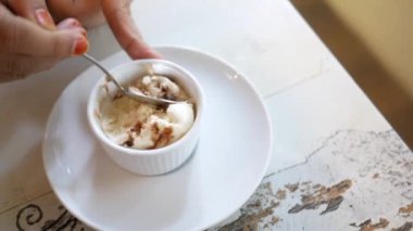 Kadınlar ellerinde kaşıkla kafe masasında dondurma yiyorlar. 