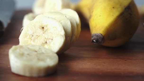 Plasterek banana bananowego na desce do krojenia na stole . — Wideo stockowe