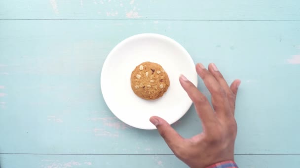 Χέρι πάρει ολόκληρο το γεύμα cookies σε ξύλινο φόντο — Αρχείο Βίντεο