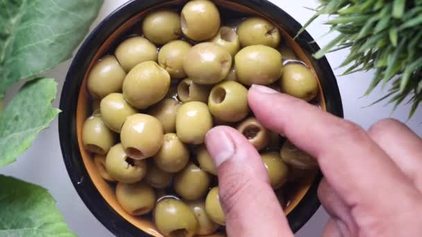 Бутылка оливкового масла и свежей оливки в контейнере на столе . — стоковое видео