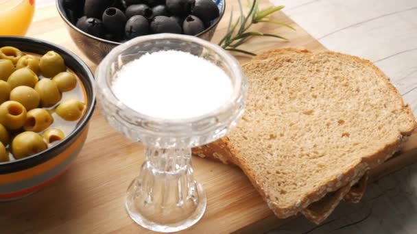 Brązowy chleb, sok, świeża zielona czarna oliwka w pojemniku na stole . — Wideo stockowe
