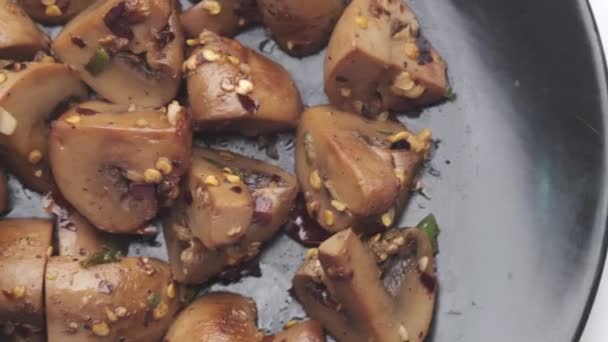 Σοταρισμένα μανιτάρια με σκόρδο και μαϊντανό σε μαύρο πιάτο σε λευκό φόντο — Αρχείο Βίντεο