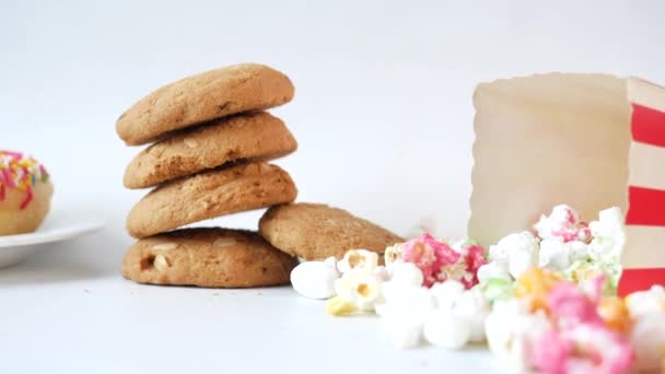 Pila de galletas, rosquillas y palomitas de maíz en la mesa — Vídeo de stock