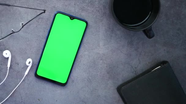 Widok z góry smartfona z zielonym ekranem słuchawki i notatnik na stole — Wideo stockowe