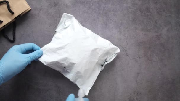 Mão em luvas de borracha azul segurando spray garrafa limpeza entrega pacote — Vídeo de Stock