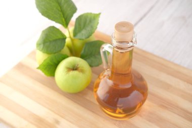 Cam şişede elma sirkesi ve masada taze yeşil elma. 
