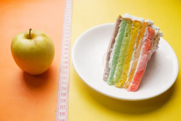 Mätning tejp, grönt äpple och ett bageri tårta på färg bakgrund — Stockfoto