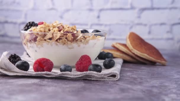 Joghurt, Müsli und Beeren in Schale auf schwarzem Hintergrund — Stockvideo