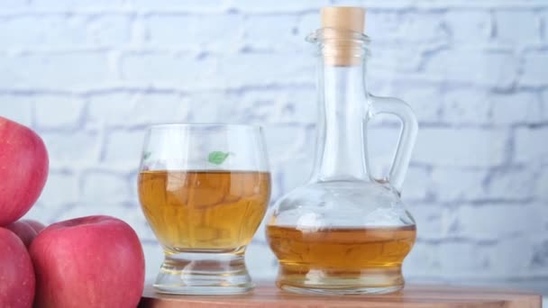 Vinaigre de pomme en bouteille en verre avec pomme verte fraîche sur la table — Video