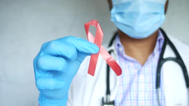 Lékař ruka drží červenou HIV stuhu s kopírovacím prostorem — Stock video