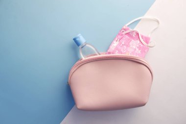 Cerrahi maskeler, termometre ve el dezenfektanı küçük çantada. 