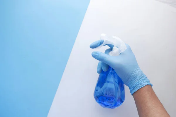 Hand in blauwe rubberen handschoenen met spuitfles en kopieerruimte — Stockfoto