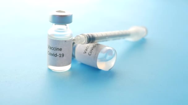 Close up da vacina contra o coronavírus e seringa sobre fundo azul — Vídeo de Stock