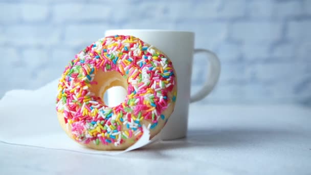 Rosquillas sabrosas coloridas y taza de café en la mesa — Vídeo de stock