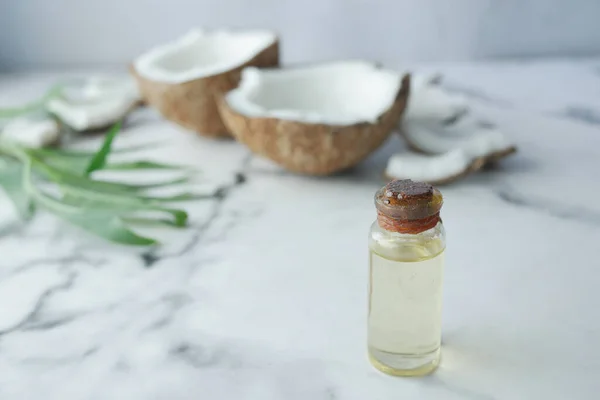 Rebanada de coco fresco y botella de aceite en una mesa — Foto de Stock