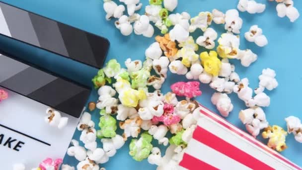 Film clapper bord en popcorn op blauwe achtergrond — Stockvideo