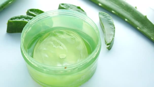 Aloe vera fresco em fatias e gel líquido em recipiente de plástico sobre fundo branco — Vídeo de Stock