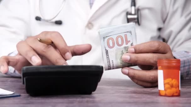 Mano del doctor sosteniendo efectivo y contando dinero en la calculadora — Vídeos de Stock