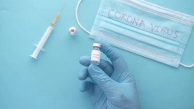 Ellerinde cam ampul aşısı tutan lateks eldivenler var. 