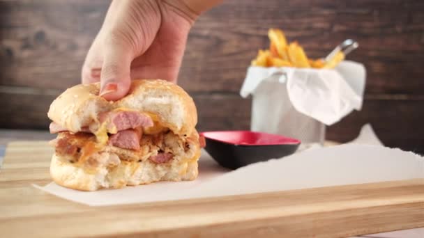 Рука держит говяжий бургер на столе близко — стоковое видео