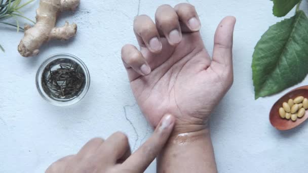 Человек нанесения и обмена сообщениями с маслом и травами на болезненную руку — стоковое видео