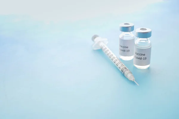 Vacuna contra el coronavirus y jeringa sobre fondo azul — Foto de Stock