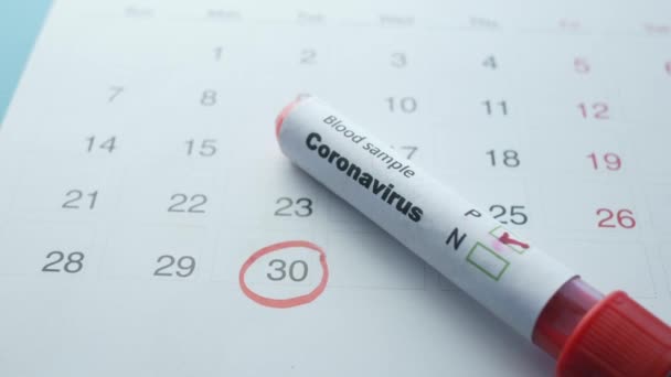 Close-up van de bloedreageerbuis en de kalender van het corona-virus op tafel — Stockvideo