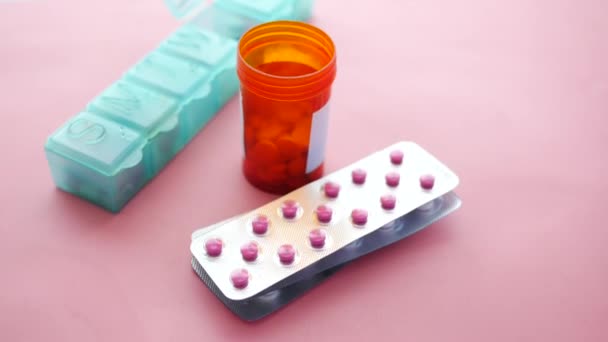 A buborékcsomagolás, tablettadoboz és tartály közelsége rózsaszínű alapon — Stock videók